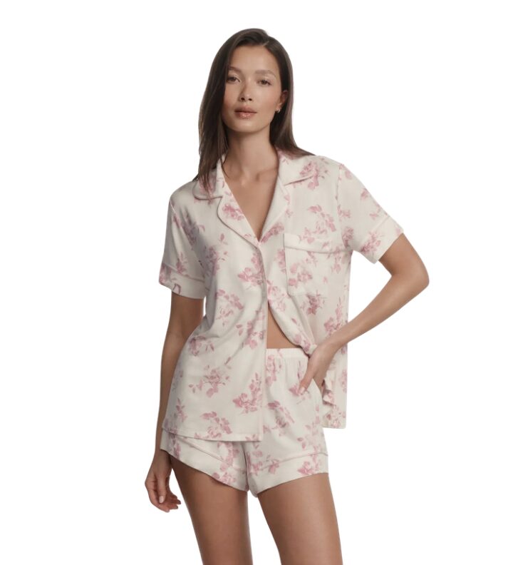Cream pajama set with pink floral print: short-sleeve button-up top and matching shorts, model standing.