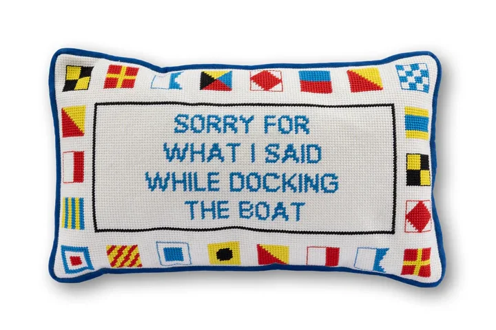 Decorative rectangular pillow with a blue border and nautical flag border, showing the text: "Sorry for what I said while docking the boat" in blue letters.
