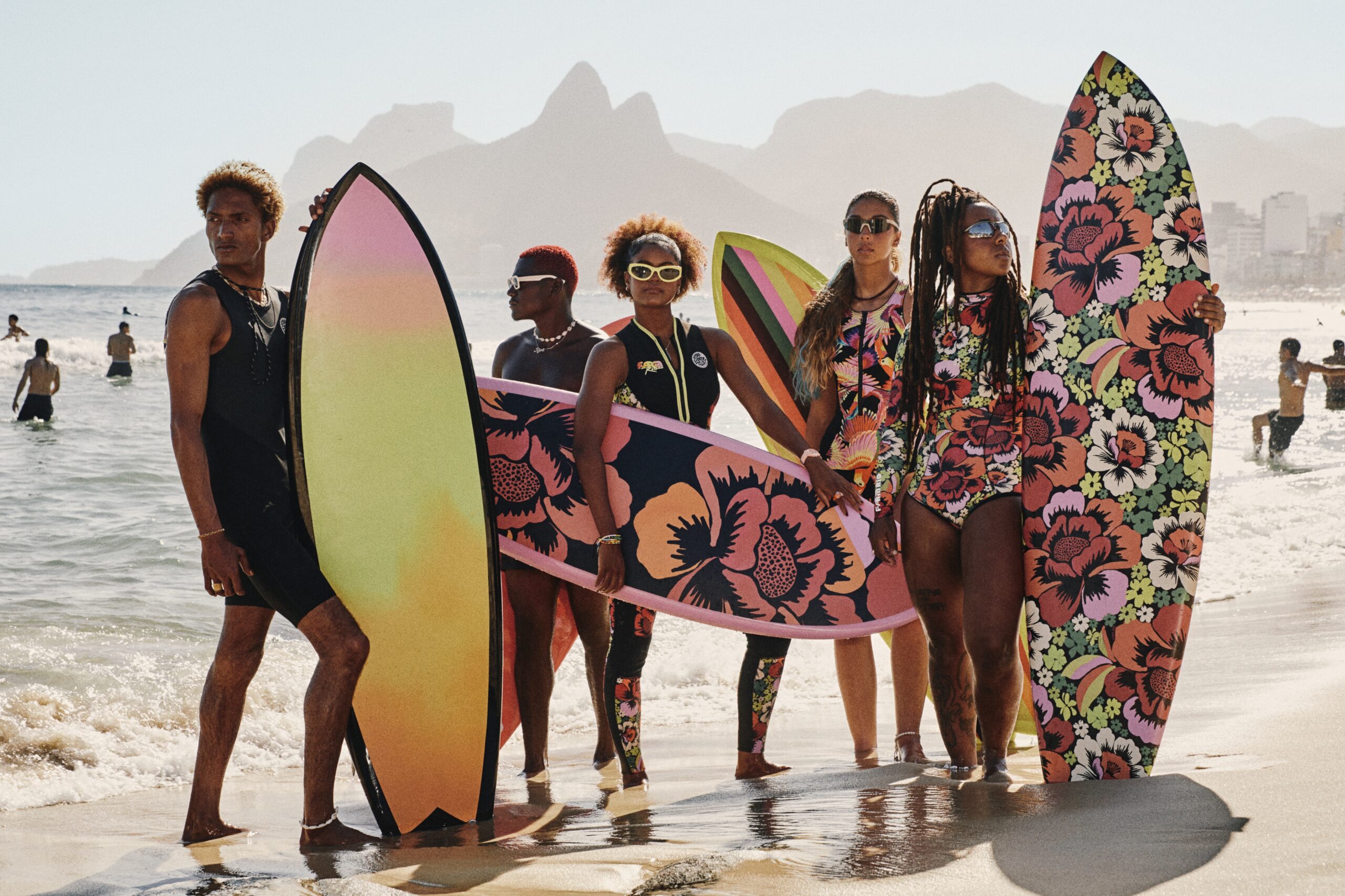 Farm Rio Rip Curl surf collection group of riders with floral print boards on the beach