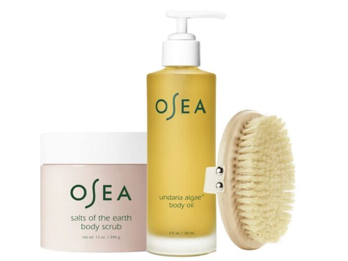 Set of OSEA body care products: Salts of the Earth body scrub, Undaria algae body oil, and a natural bristle body brush on a white background.