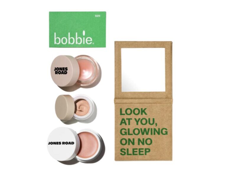 Jones Road makeup jars arranged beside a kraft bag with a square window and the slogan 'LOOK AT YOU, GLOWING ON NO SLEEP'