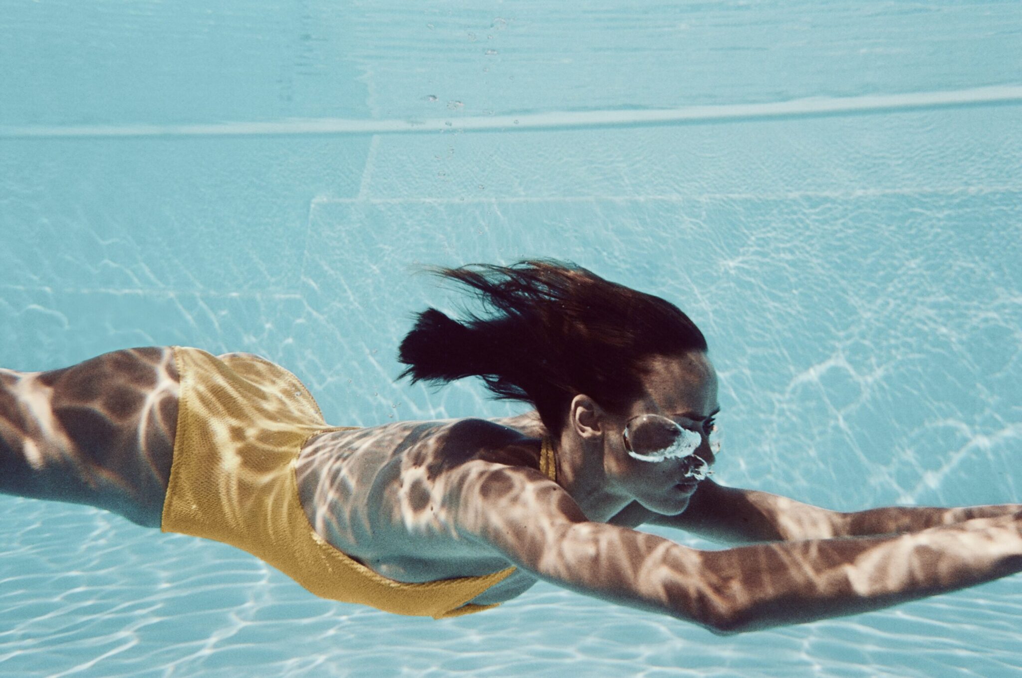 Woman swimming underwater in a stylish one-piece swimsuit