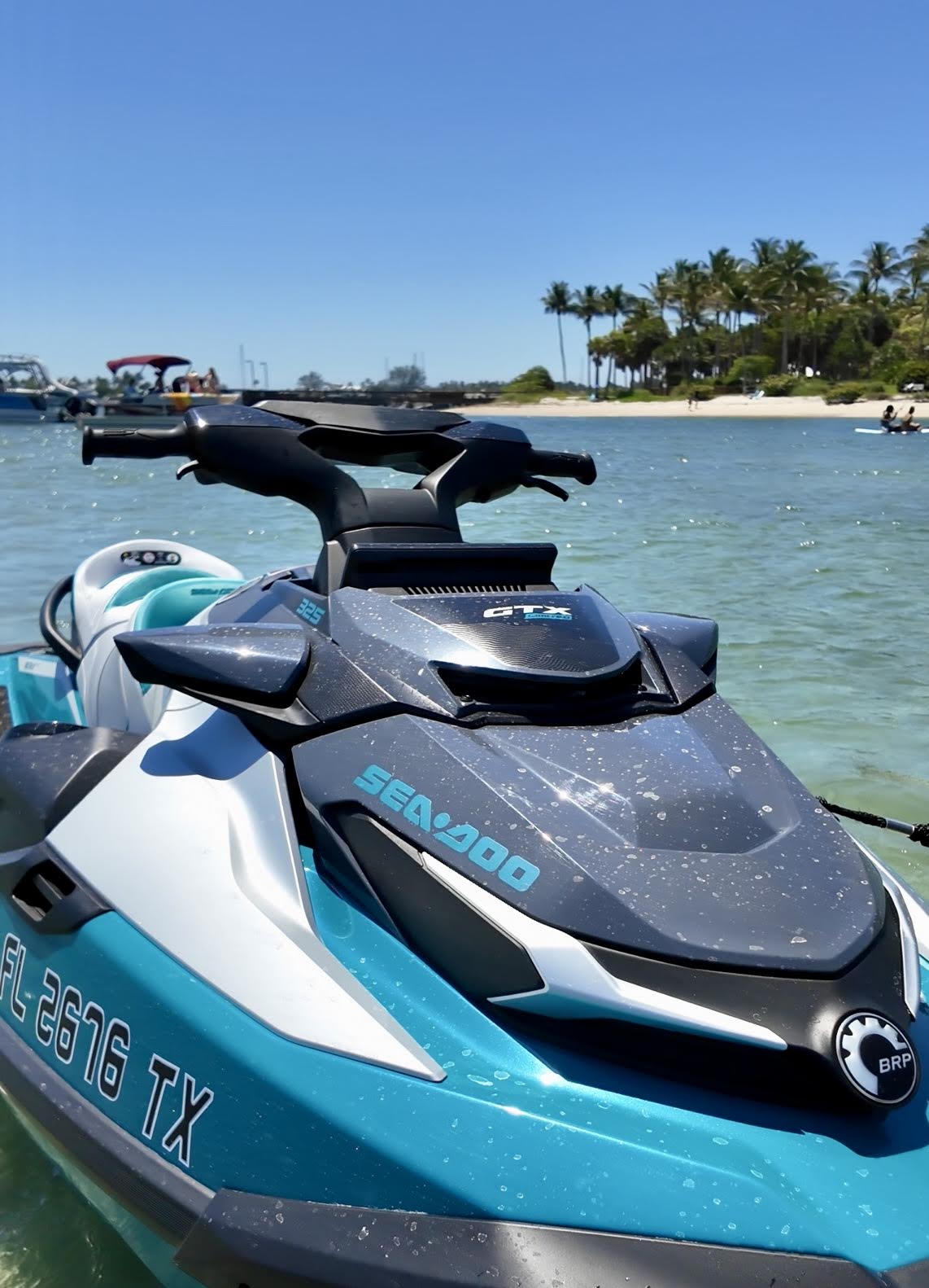 Screenshot - The Wake Edit Blue and white Sea-Doo GTX jet ski anchored near a tropical beach with palm trees in the background.