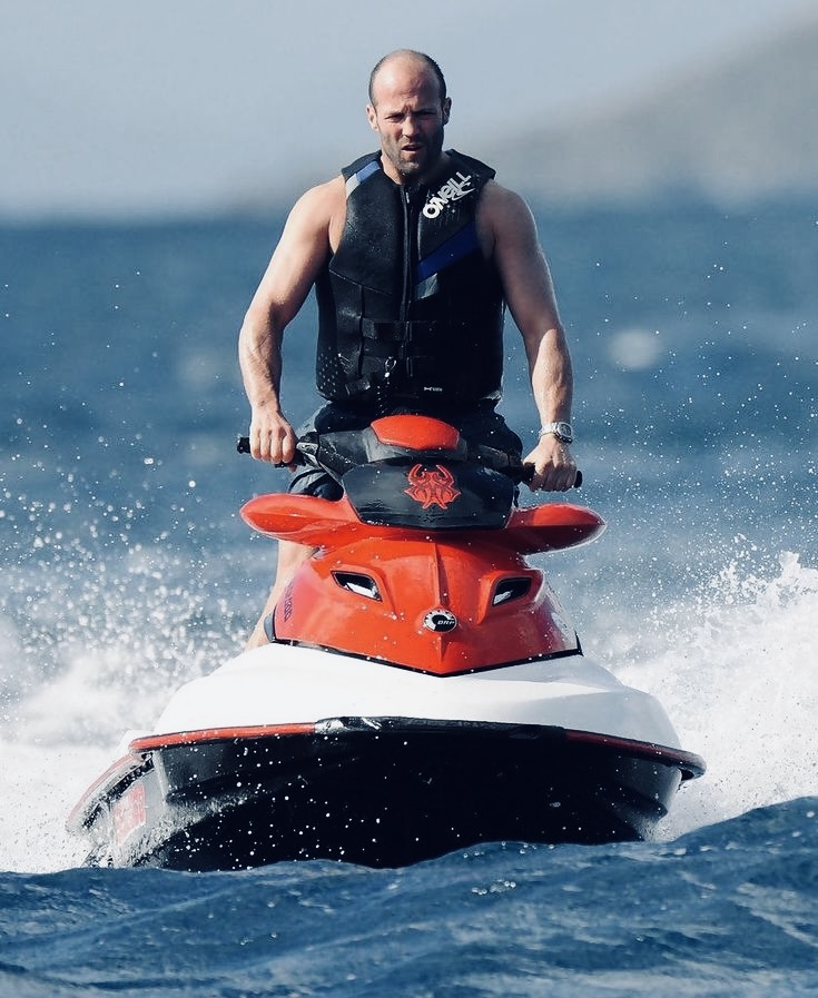 Jason Statham's practical jet ski look with board shorts and a fitted life jacket