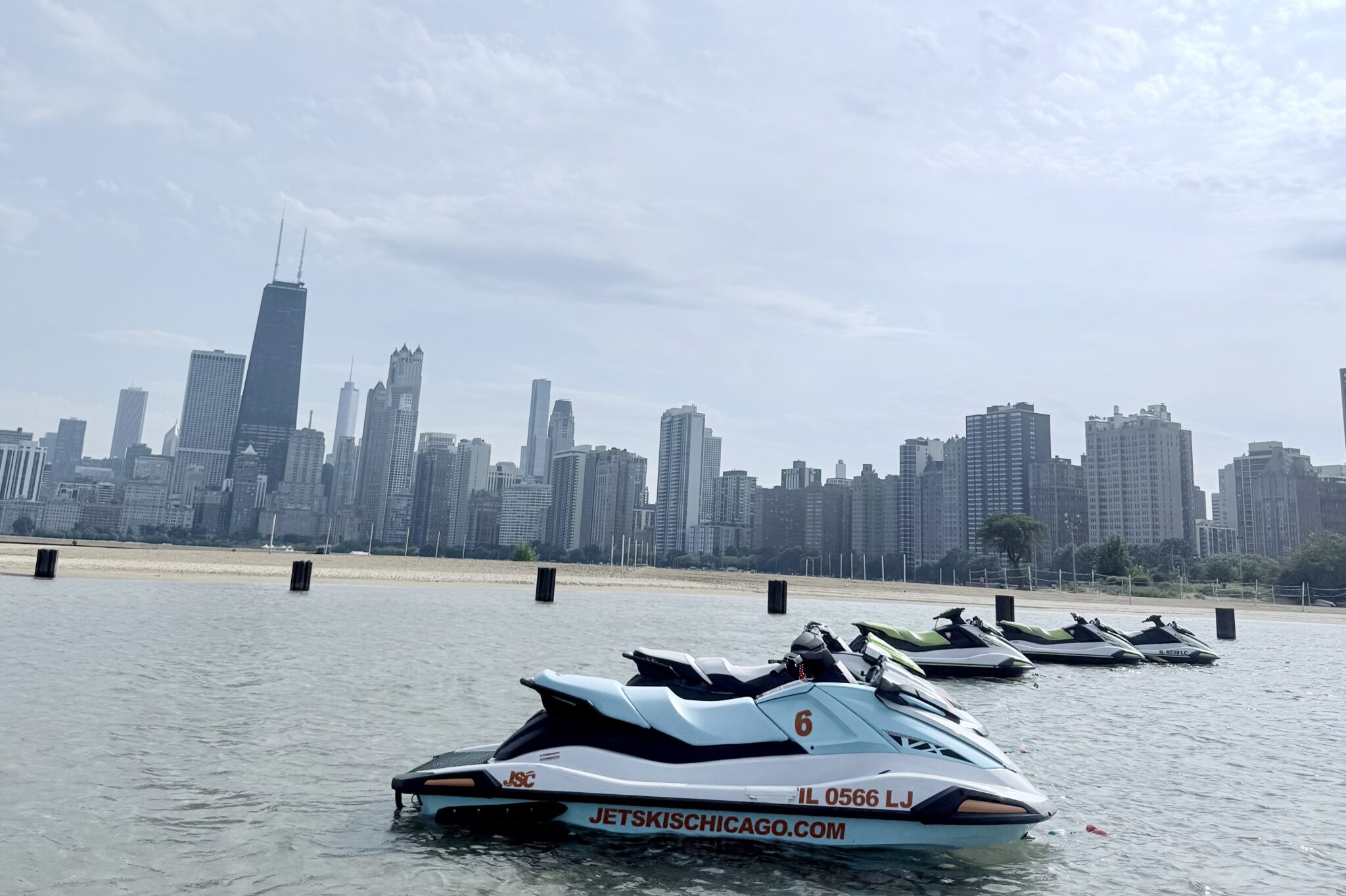 MAIN - The Wake Edit Jet skis docked on a calm river with Chicago's skyline in the background under a cloudy sky